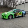 Bright green auto wrap on hybrid service vehicle for The Hybrid Doctor, featuring bold branding, phone number, and service details.