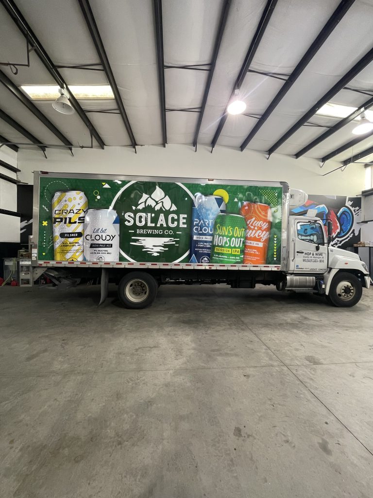 Large-format auto wrap on Solace Brewing Co. delivery truck displaying beer branding and product imagery across the full vehicle side.